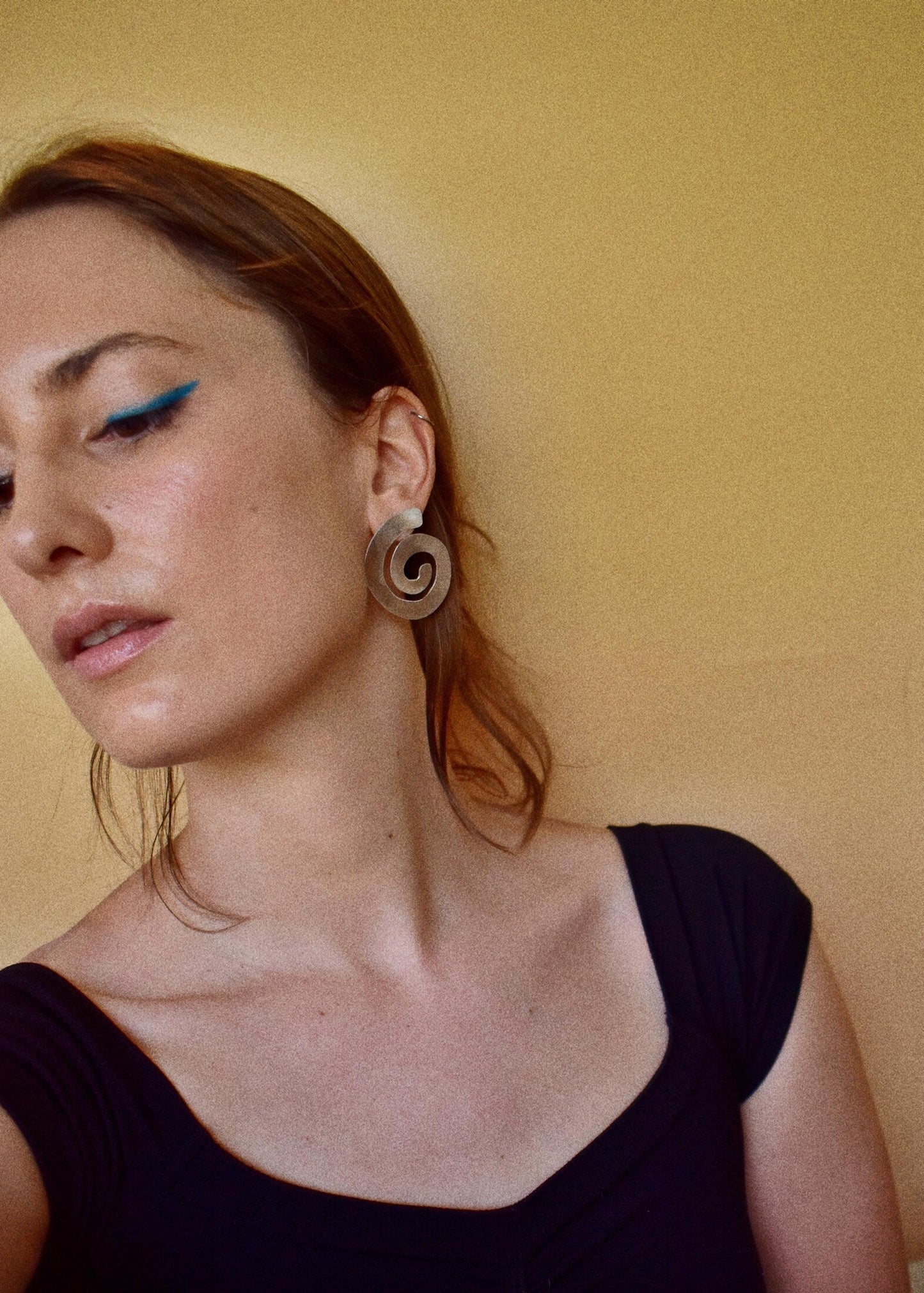 Woman wearing a unique earring against a plain background