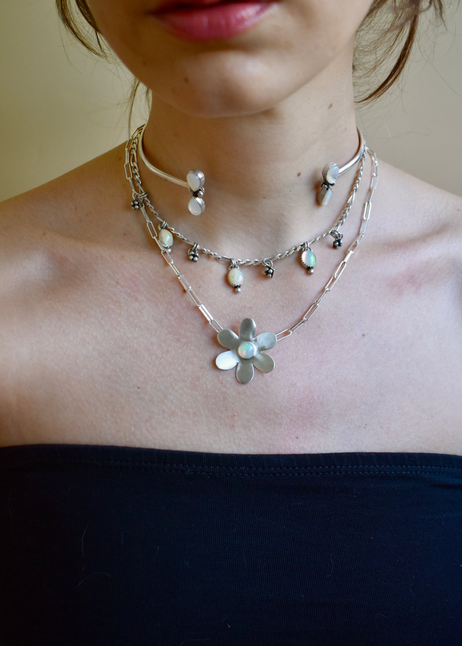 Necklace with a flower pendant worn by a person against a neutral background