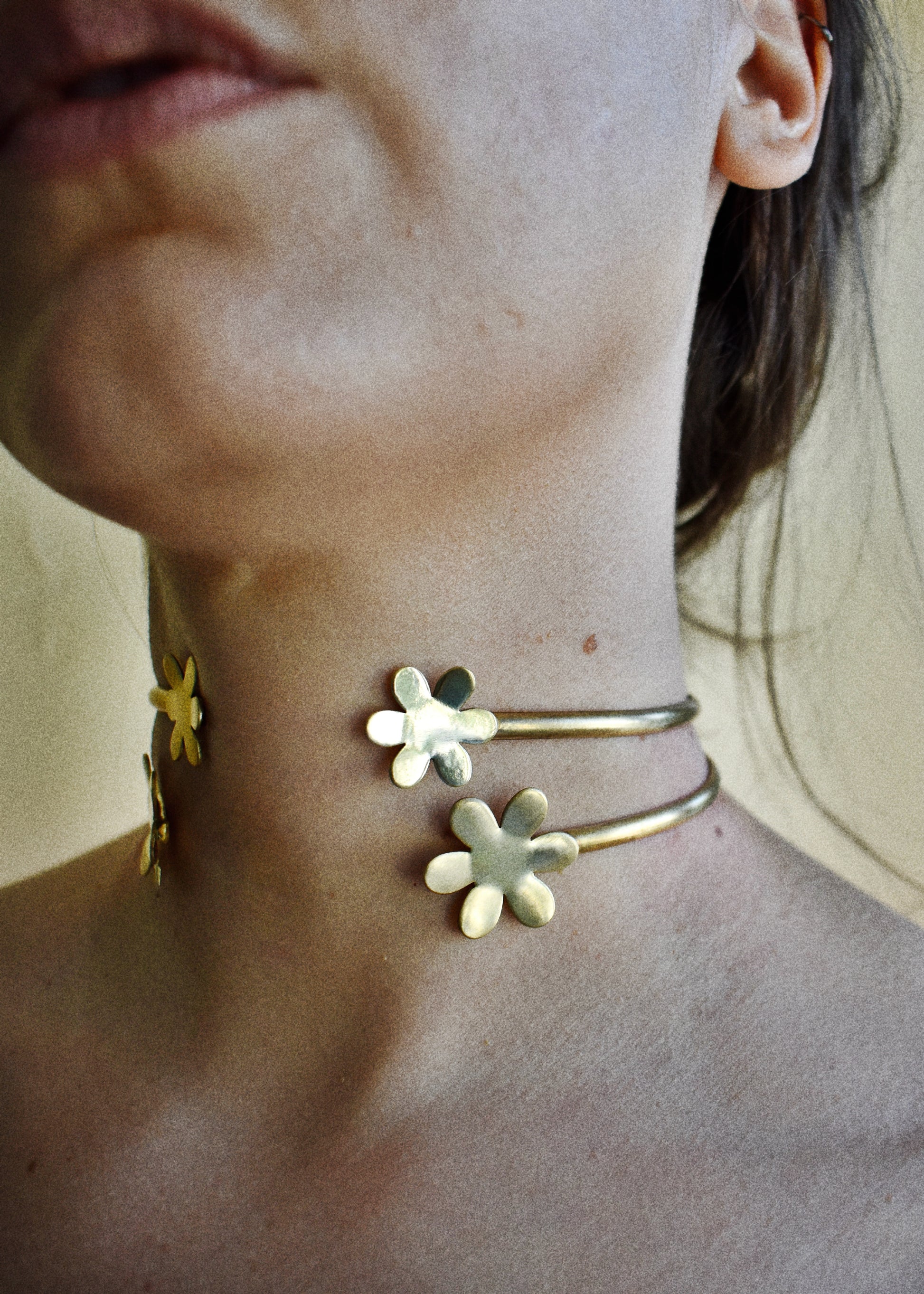 Close-up of a person wearing gold flower-shaped earrings and a necklace.